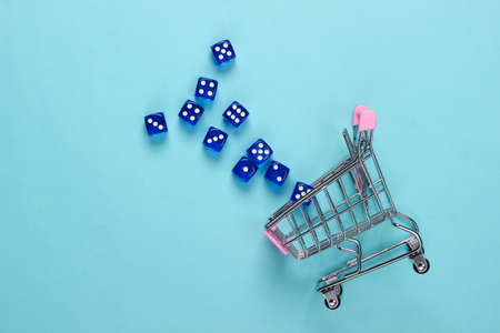 Shopping cart with dice on a blue pastel background. Good luck shopping. Top viewの写真素材