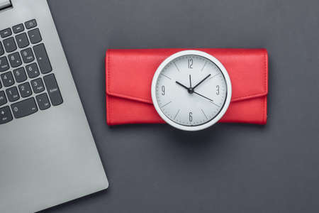 Time to make money.Online business. White clock, laptop and red wallet on gray background. Minimalistic studio shot. Top viewの写真素材