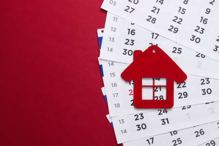 Payment of rent for housing. Figurine of a house with a monthly calendar on a red background.の写真素材