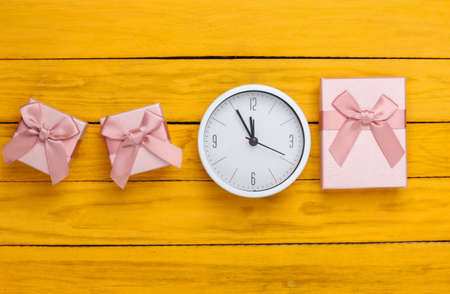 Christmas, New Year theme. Gift boxes with clock on yellow wooden background. Top viewの写真素材