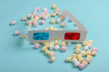 Anaglyph disposable paper 3d glasses with marshmallows on a blue background. Pop art, minimalismの写真素材