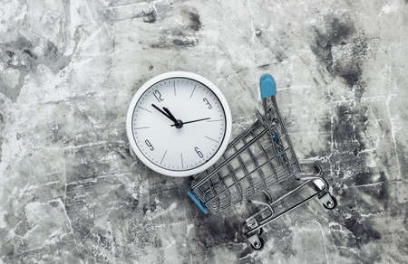 Shopping time. Supermarket trolleys with clock on gray concrete background. Minimalism. Top viewの写真素材