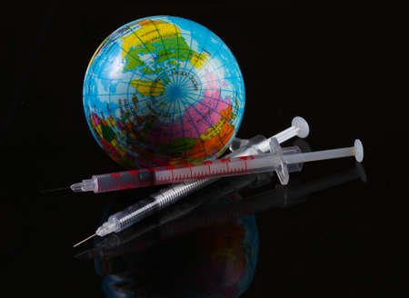 Syringe and globe on black background. Global vaccination.の写真素材