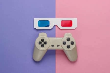 Anaglyph disposable paper 3d glasses and retro gamepad on purple pink background. Top view