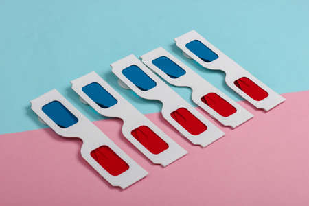 Many stereoscopic anaglyph disposable paper 3d glasses on pink blue pastel background.