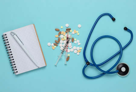 Medical theme. Syringes, pills, stethoscope and notebook on blue background. Top viewの写真素材