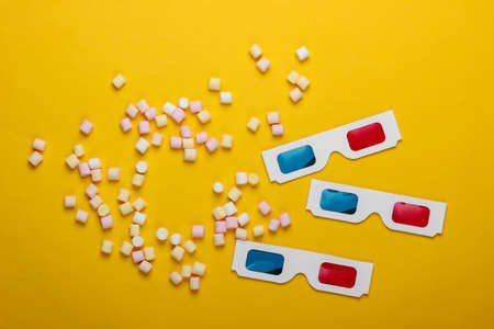 Anaglyph disposable paper 3d glasses with marshmallows on a yellow background. Top view. Pop art, minimalismの写真素材