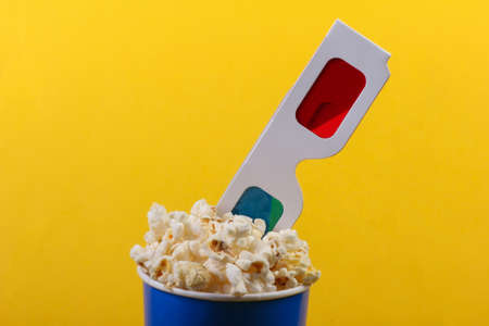 Movie time. Cardboard bucket of popcorn with Stereoscopic anaglyph disposable paper 3d glasses on...