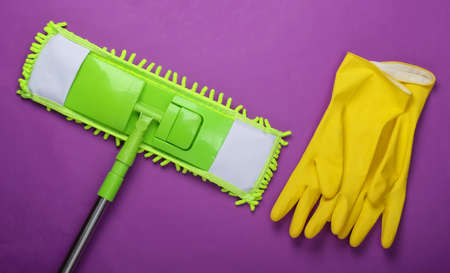 Plastic green mop, gloves on purple background. Disinfection and cleaning in the house. Top view