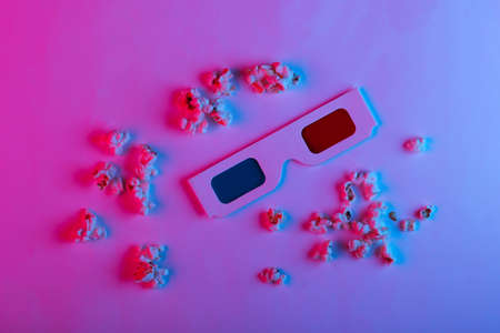 Movie time. Stereoscopic anaglyph disposable paper 3d glasses with popcorn in pink blue gradient neon light.の写真素材