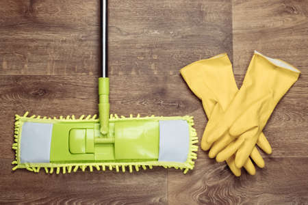 Plastic green mop, gloves on wooden floor. Disinfection and cleaning in the house. Top viewの写真素材