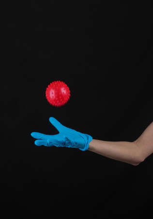 Hand in a protective medical glove throws up a covid-19 virus strain model on a black backgroundの写真素材