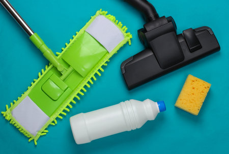 Cleaning products. Mop, vacuum cleaner head, bottles of detergent, sponges on blue background. Disinfection and cleaning in the house. Top viewの写真素材