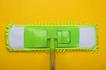 Plastic green mop on yellow background. Disinfection and cleaning in the house. Top viewの写真素材