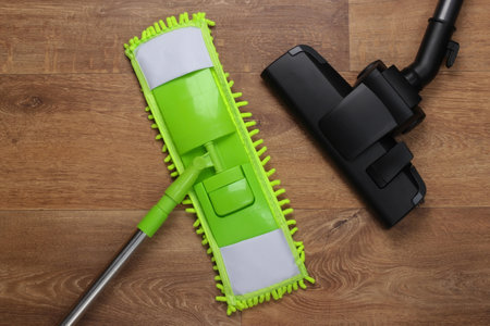 Plastic mop and vacuum cleaner head on wooden floor. Disinfection and cleaning in the house. Top viewの写真素材