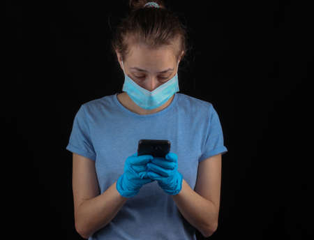 Communication during the quarantine period. Woman in medical gloves and a face mask is typing in a...