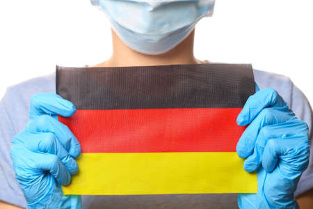 Pandemic covid-19 theme. Woman in protective gloves, medical face mask holds Germany flag isolated on white background.の写真素材