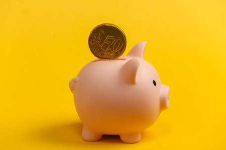Piggy bank with coin on yellow background.の写真素材