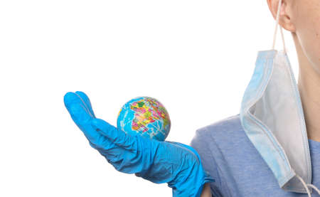 Overcoming Pandemic theme. Woman in protective gloves, medical face mask holds Globe model isolated on white background.の写真素材