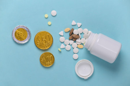 Bottle of pills with coins on a blue background. Top viewの写真素材