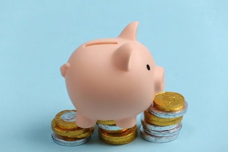 Piggy bank with stack of coins on blue background.