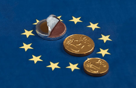 Chocolates in the shape of euro coins on Euro Union flag backgroundの写真素材
