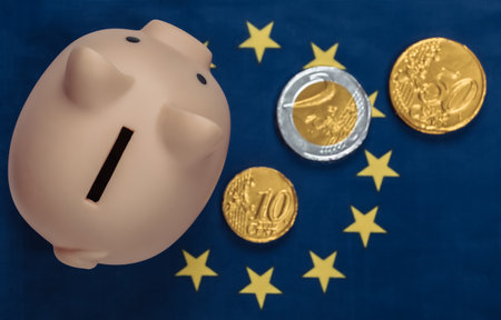 Piggy bank with coins on the background of the Euro Union flagの写真素材