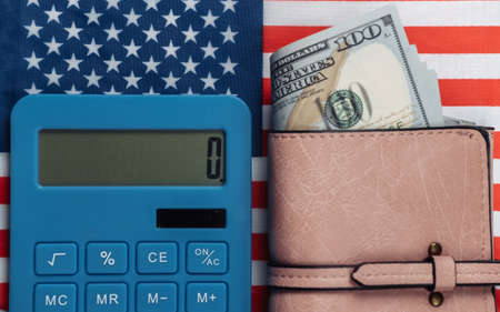 Leather wallet with hundred dollar bills, calculator on background of USA flag.の写真素材