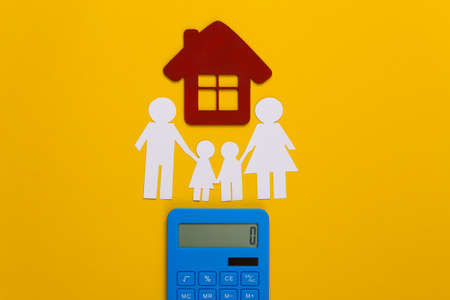 Paper happy family together with house, calculator on yellow background. Calculation of family expenses, budgetの写真素材