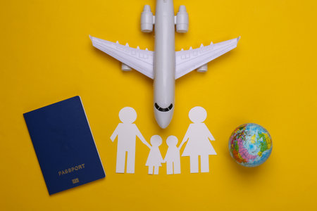Travel or family immigration. Paper family together, plane, globe and passport on yellow background.の写真素材