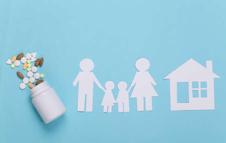 Paper chain family with house, bottle pills on blue background, health insurance conceptの写真素材