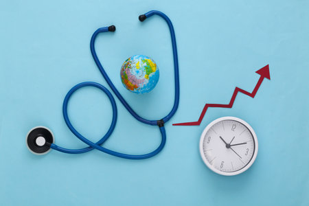 Global medicine concept. Stethoscope with globe, clock and growth arrow on blue background. Top viewの写真素材