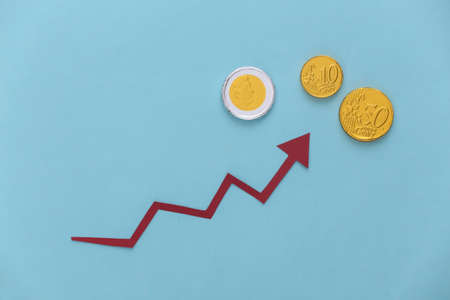 Red growth arrow and coins on blue background. Arrow graph going up. The economic growthの写真素材