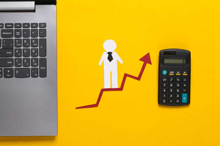 Laptop, paper business man on growth arrow with calculator. Yellow background. Symbol of financial and social success, stairway to progress. Career ladder.の写真素材