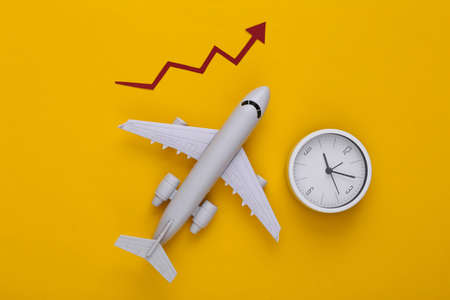 Airplane with growth arrow and clock on a yellow background. Top viewの写真素材