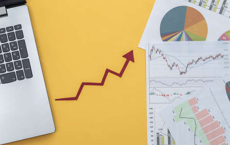 Growth upward arrow, graphs and charts with laptop on yellow background. Online business. Business success. Top viewの写真素材