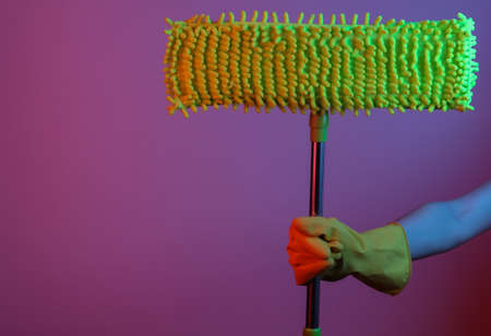 Hand with gloves hold a mop in blue-red neon gradient light