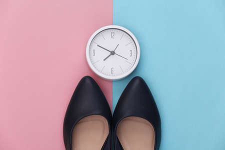 Women's shoes with heels and clock on a pink blue background. Top view