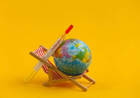 Summer Heat. Mini beach deck chair and globe, thermometer on yellow background. Symbol of beach holidays, resort. Relax, Summer minimal concept.の写真素材