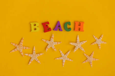 Starfish and word beach on yellow background. Symbol of beach holidays, resort. Relax, Summer minimal concept. Top viewの写真素材