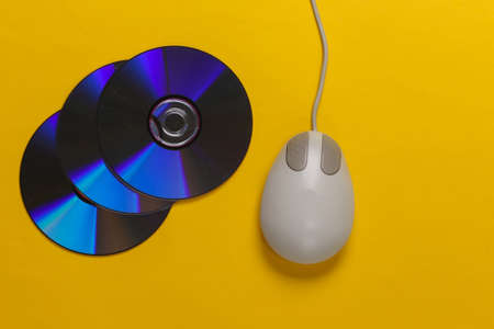 Old-fashioned retro CD's and pc mouse on yellow background. Top viewの写真素材