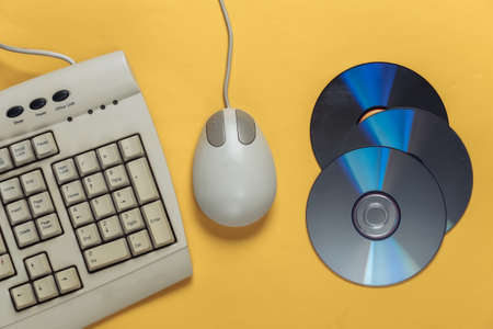Old-fashioned retro keyboardÐ± CD's and pc mouse on yellow background. Top view