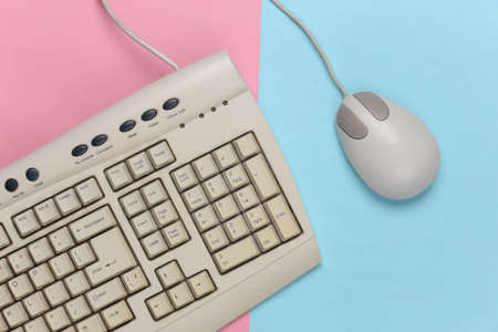 Old-fashioned retro keyboard and pc mouse on a blue-pink pastel background. Retro computer. Top viewの写真素材