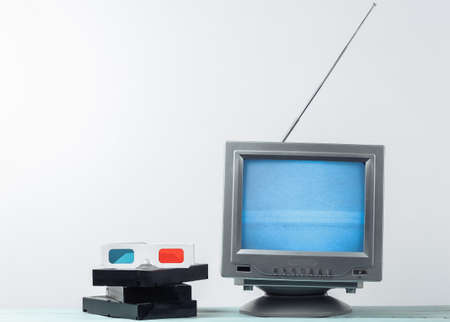 Antenna old-fashioned retro tv receiver, anaglyph 3D glasses and video cassettes on white wall...