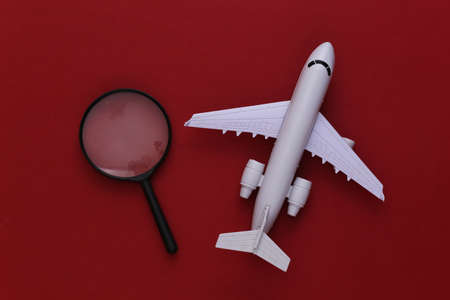 Travel concept. Airplane and  magnifier on red background. Top view. Flat layの写真素材