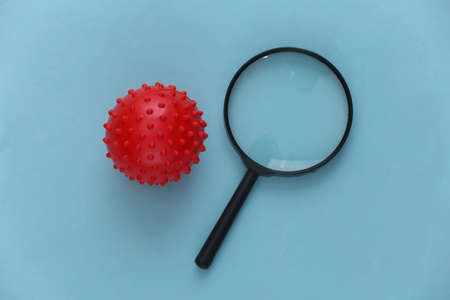 Magnifier with a model of a strain of the virus on a blue background. Top view
