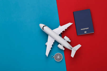 Compass and air plane, passport on red-blue background. Travel, adventure flat lay. top viewの写真素材