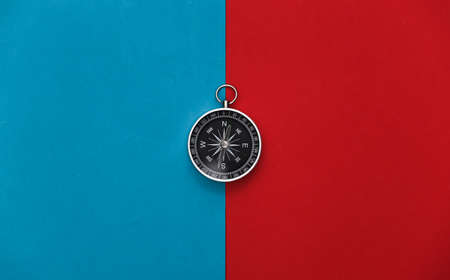 Compass on a red-blue background. Travel, adventure flat lay. top view