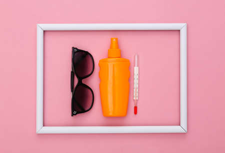beach holidays. summer background. Sunblock bottle, sunglasses and thermometer on pink background...