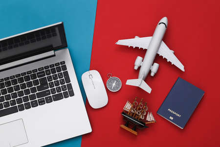 Laptop and travel accessories on red-blue background. Planning travel concept. top view. flat layの写真素材